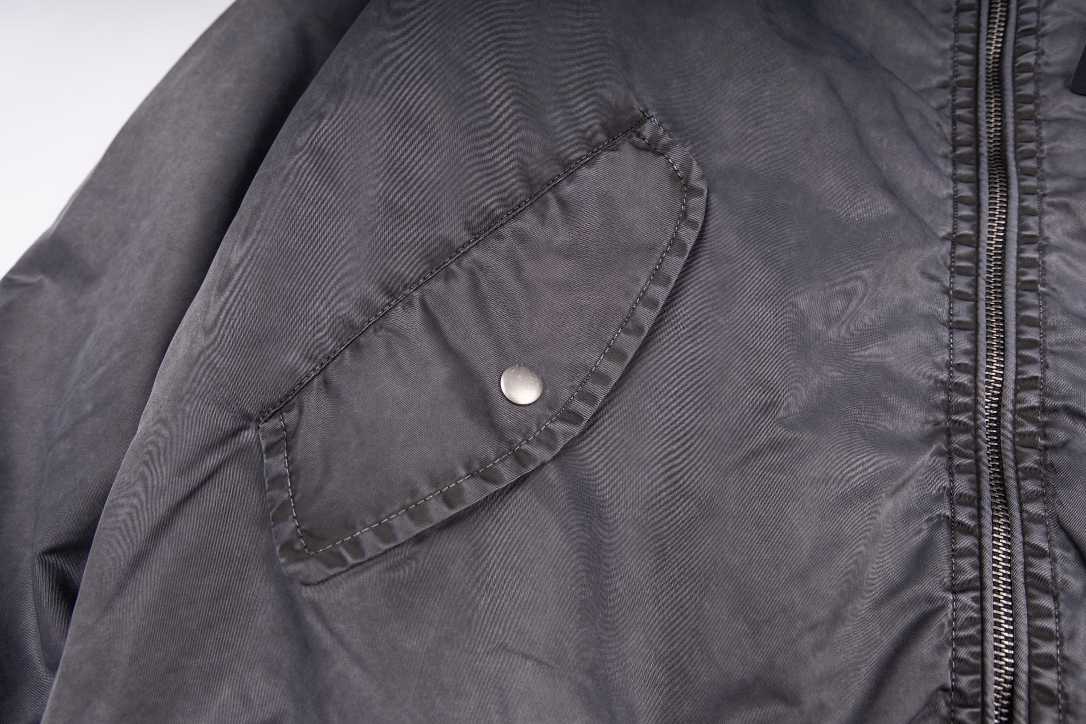 Dark gray bomber jacket with snap chest pocket and zipper track detail
