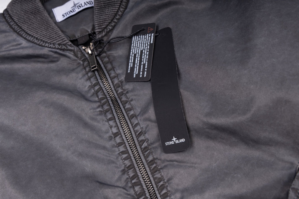 Stone Island zip-up jacket with dark zipper and logo patch, close-up neckline