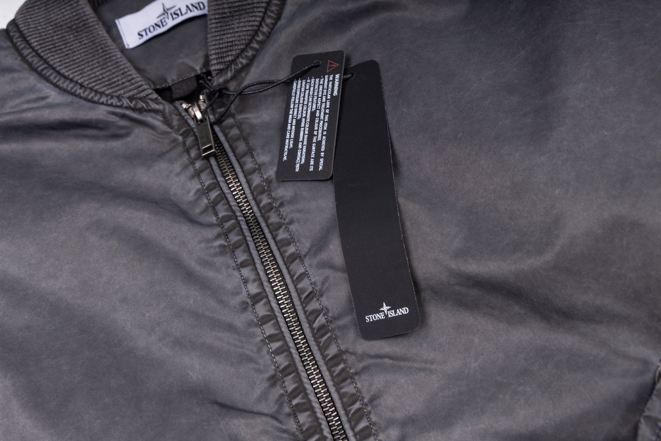 Stone Island zip-up jacket with dark zipper and logo patch, close-up neckline