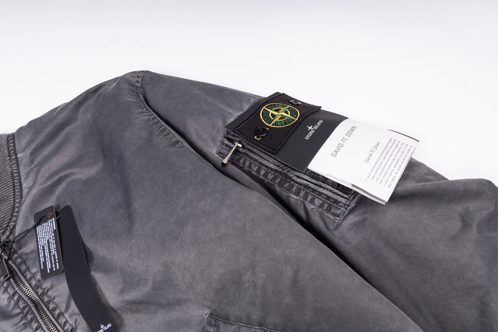 Dark gray bomber jacket with inner label and black hang tag over shoulder