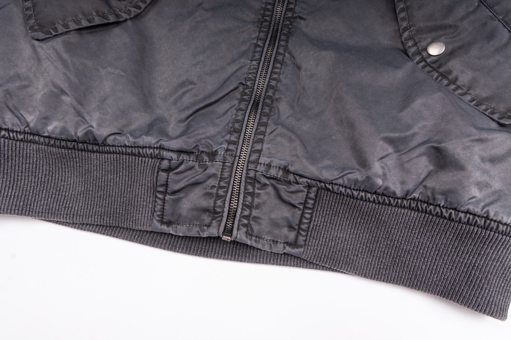 Dark gray bomber jacket front hem with central zipper and ribbed waistband