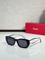 Prada sunglasses with black frame and dark gray-tinted lenses, side logo accents.