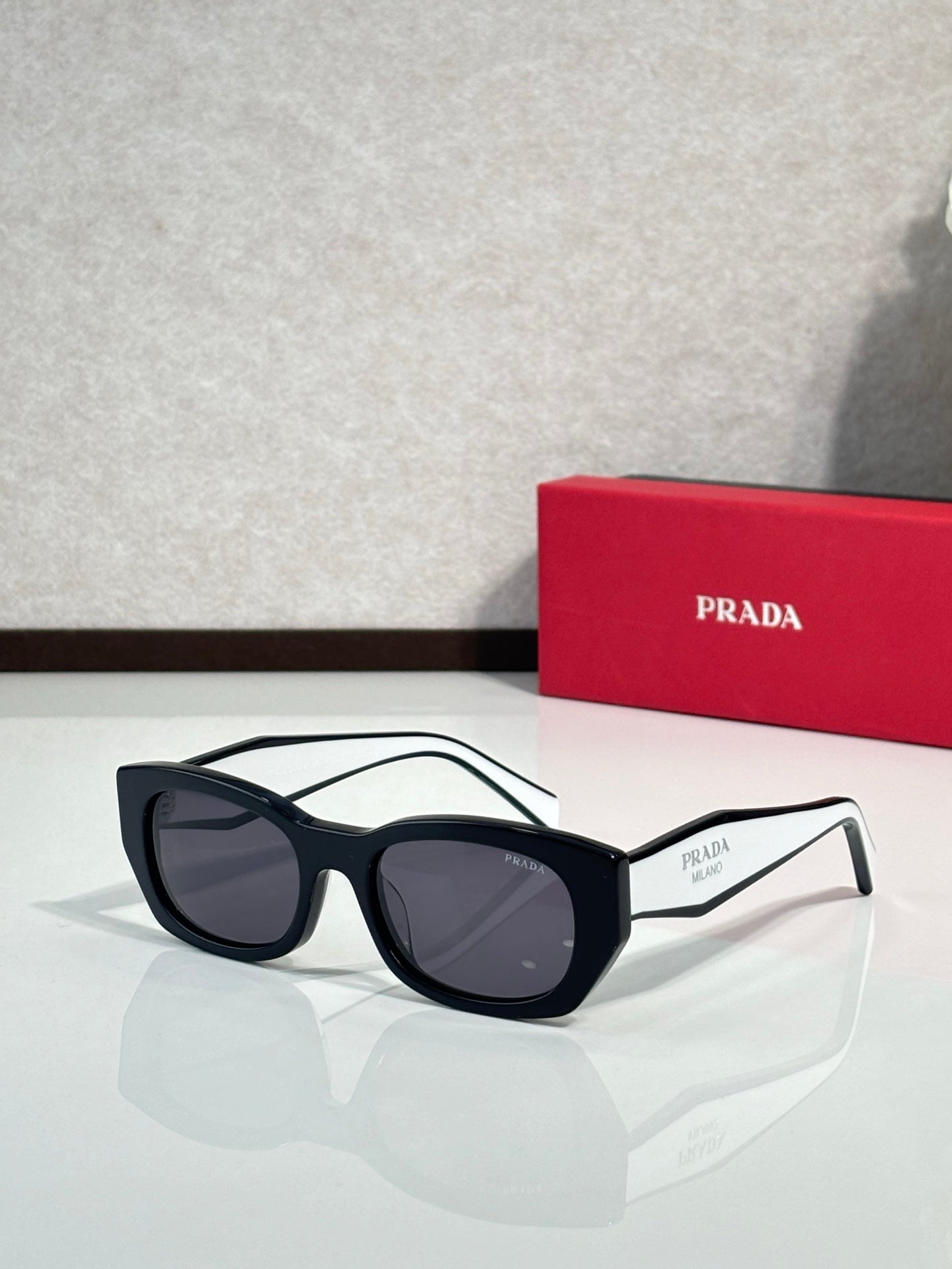 Prada sunglasses with black frame and dark gray-tinted lenses, side logo accents.