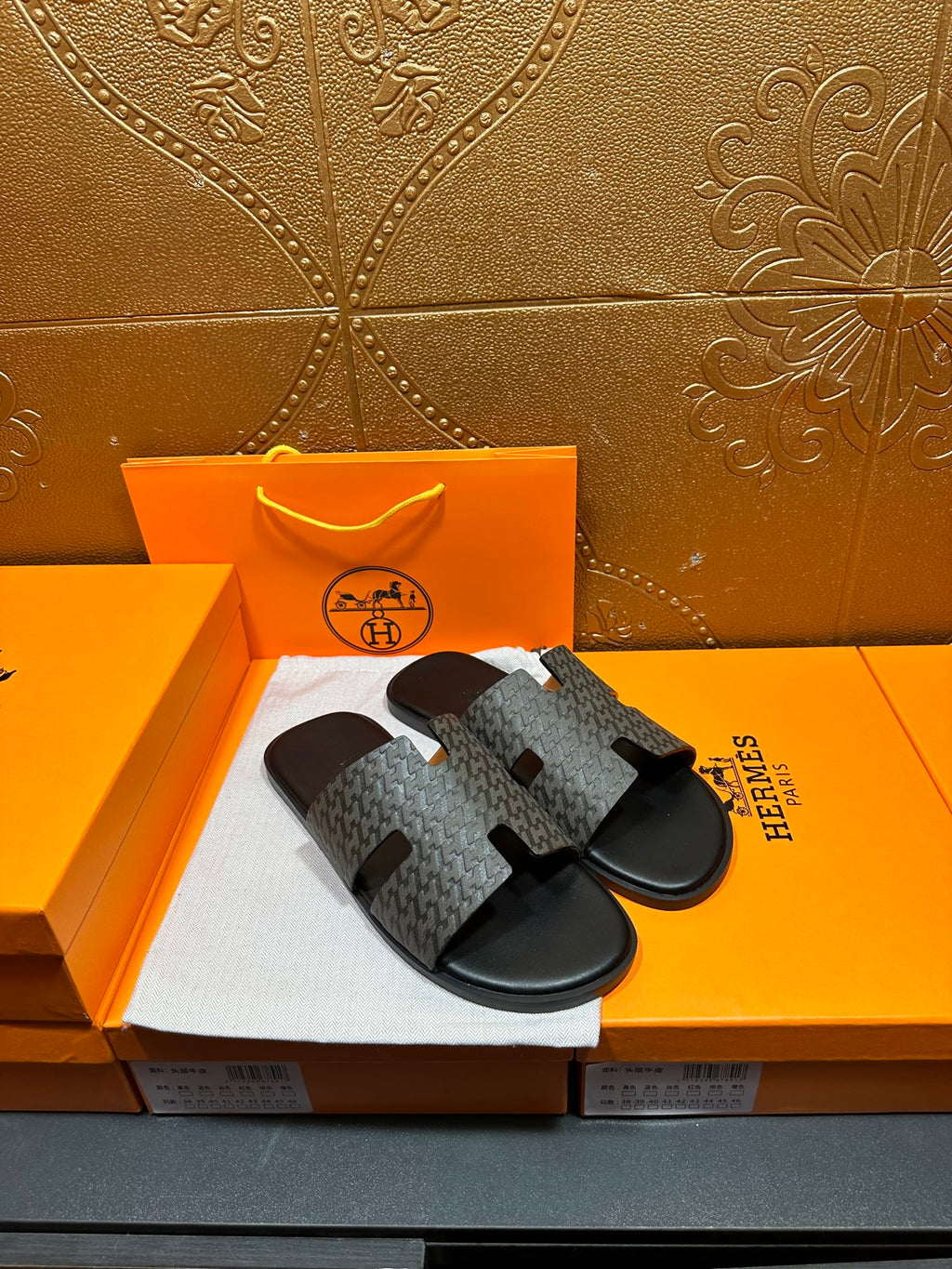 Hermes slide sandals side view with gray logo-pattern strap and black contoured footbed