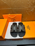 Hermes slide sandals with gray monogram-pattern straps and black rubber footbed