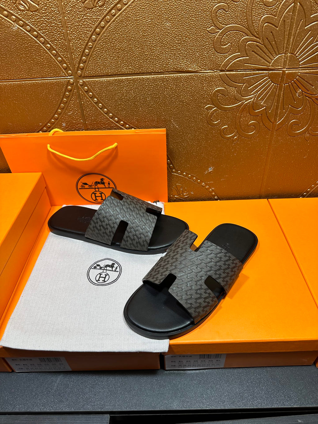 Hermes slide sandals top view, gray monogram-pattern straps on black rubber base