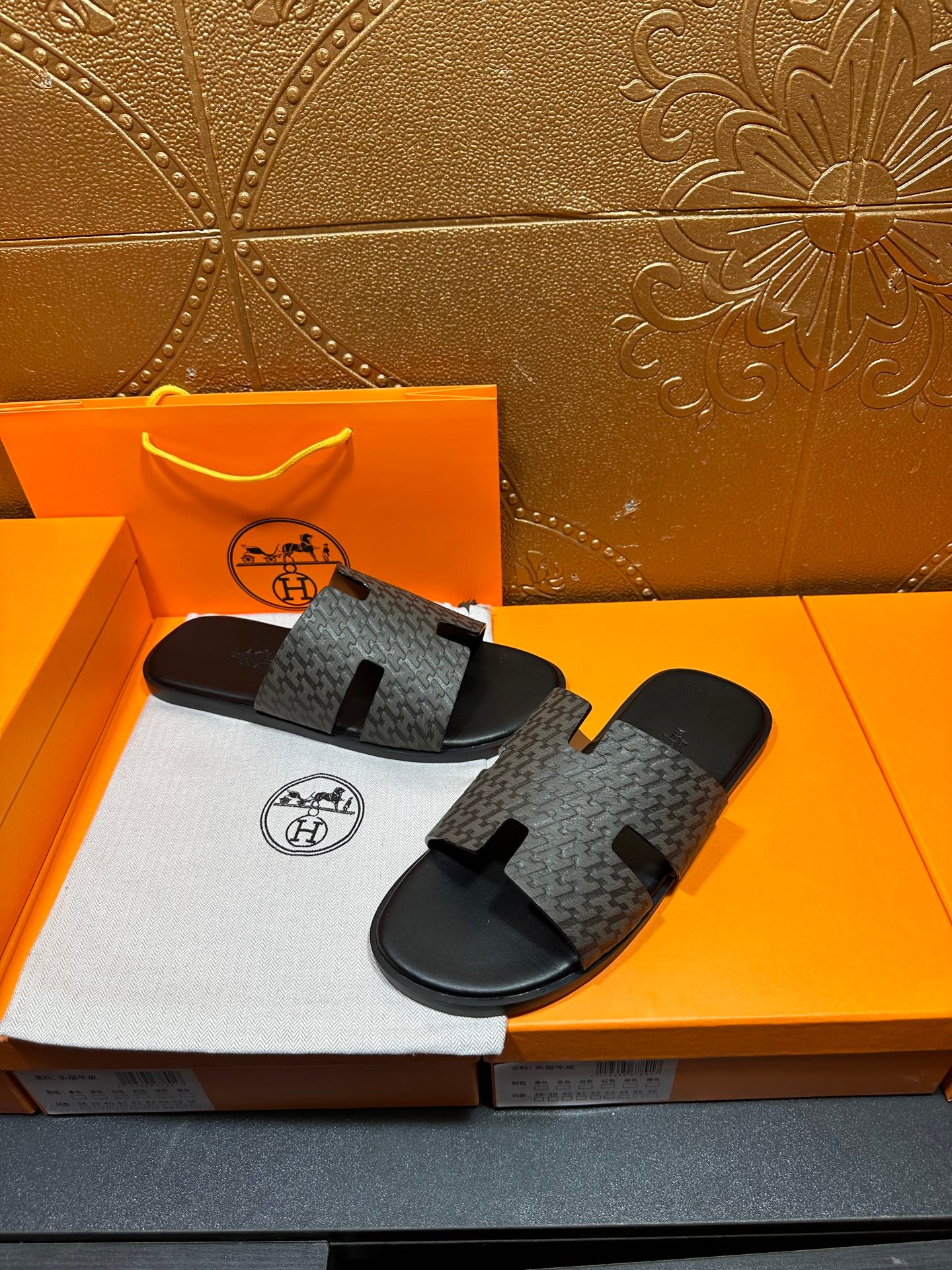 Hermes slide sandals top view, gray monogram-pattern straps on black rubber base