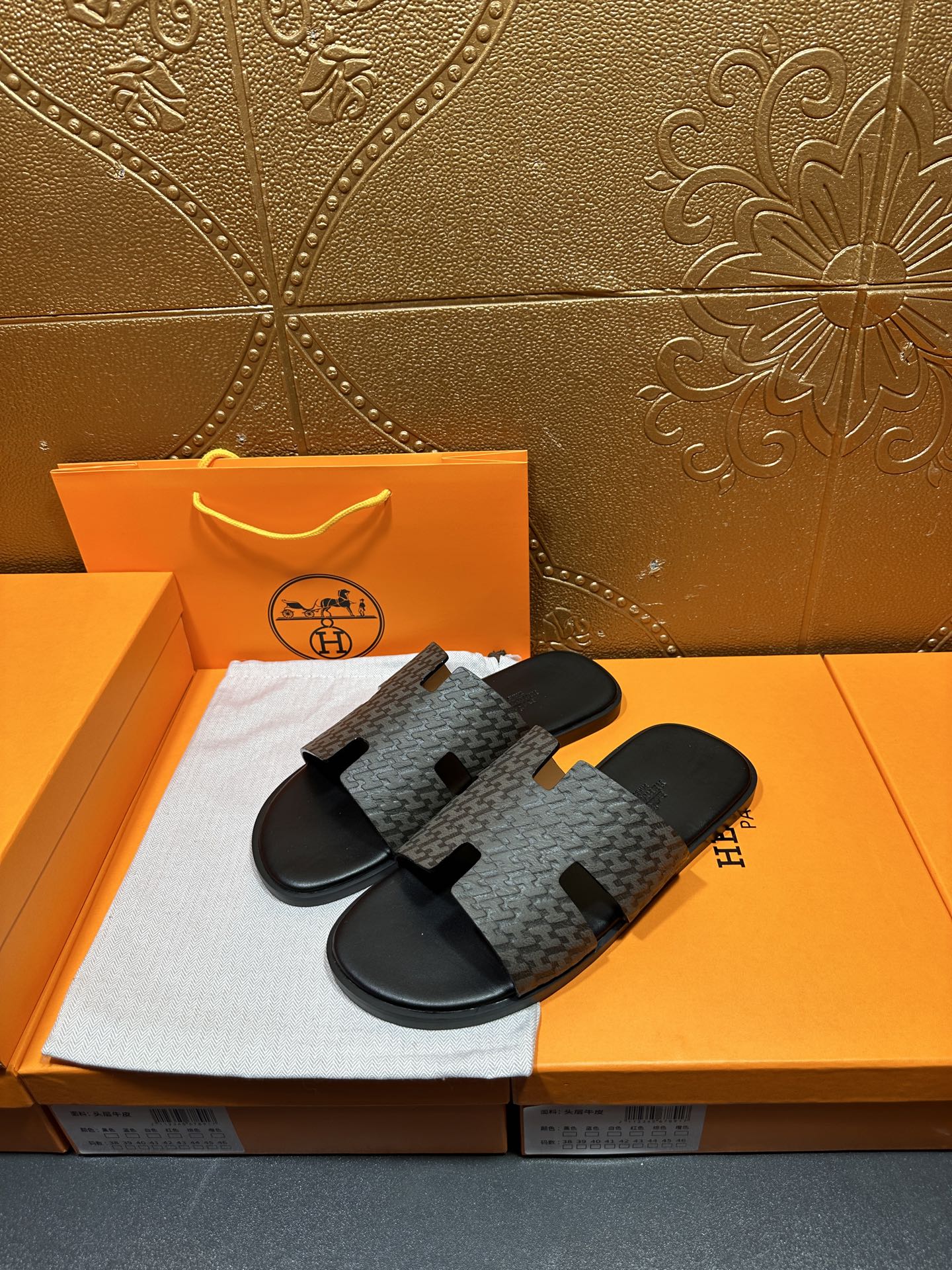 Hermes slide sandals angled view, gray patterned straps with black open-toe slides