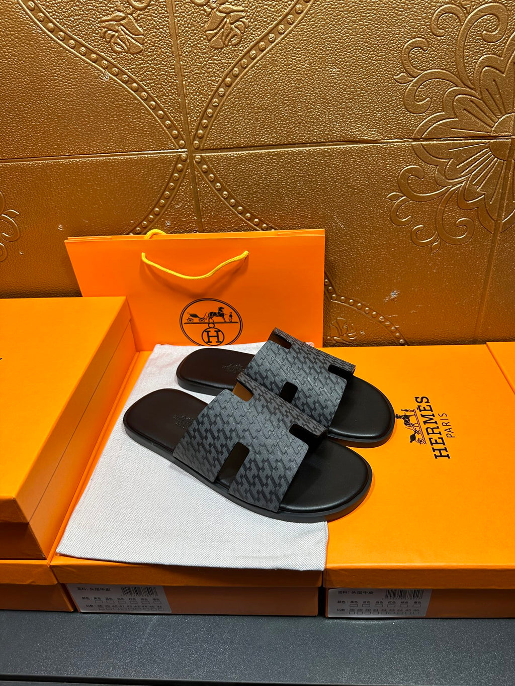 Hermes slide sandals with charcoal logo-pattern straps and black adjustable H cutouts