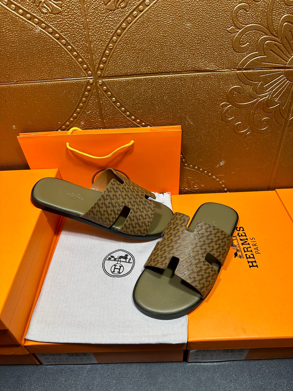 Hermes slide sandals with dark patterned straps and light gray footbeds on display