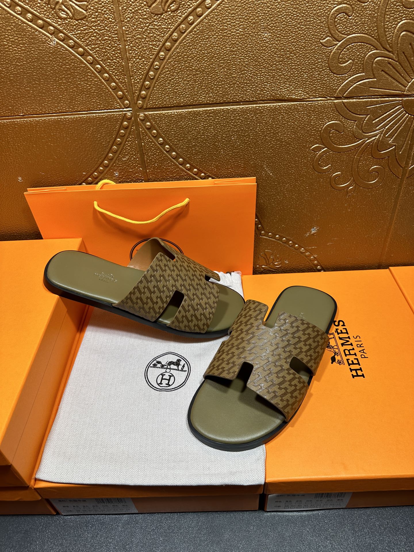 Hermes slide sandals with dark patterned straps and light gray footbeds on display