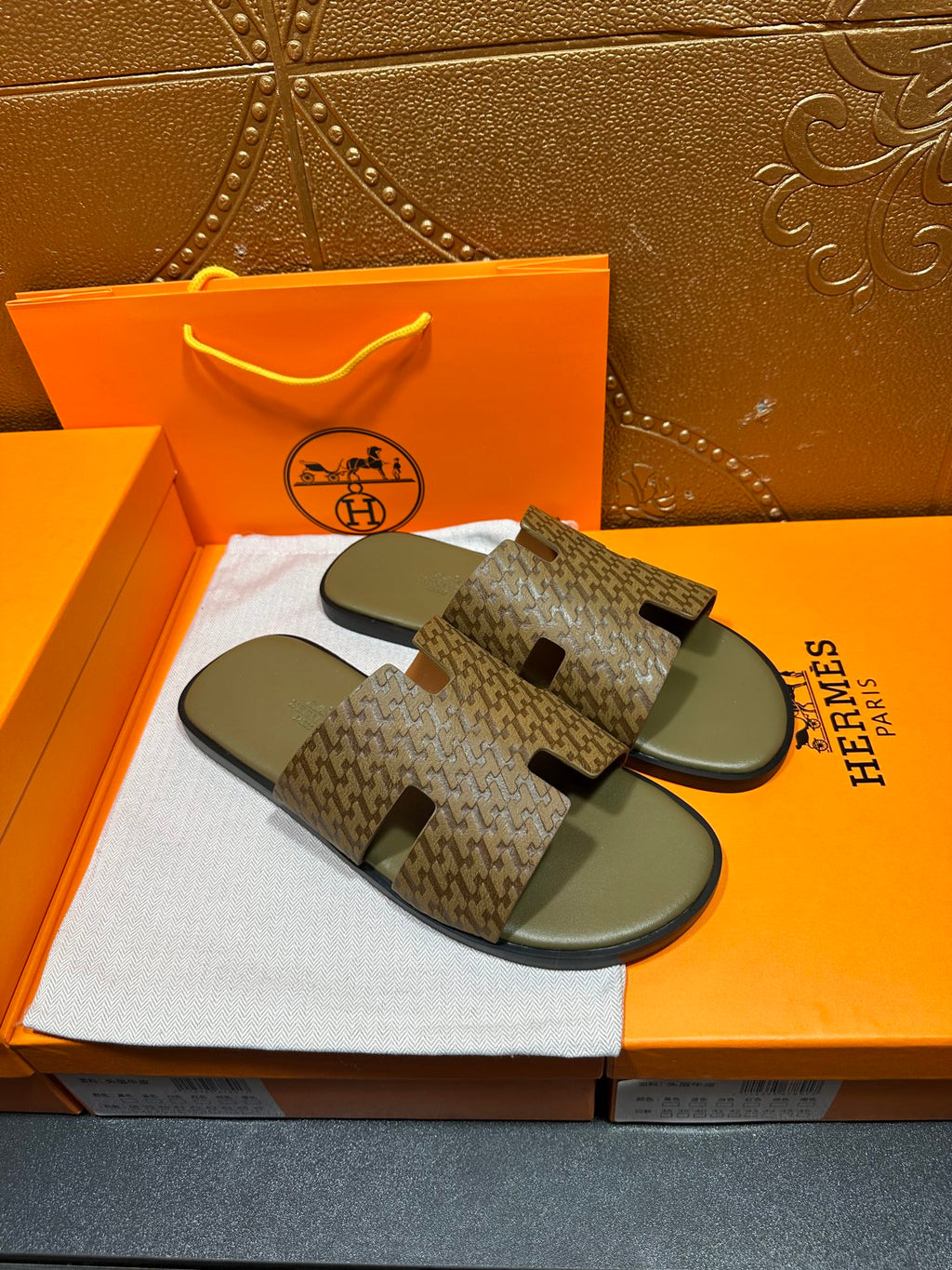 Hermes slide sandals with dark monogram-like pattern and black cutout strap tabs