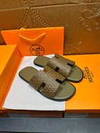 Hermes slide sandals with dark monogram-like pattern and black cutout strap tabs