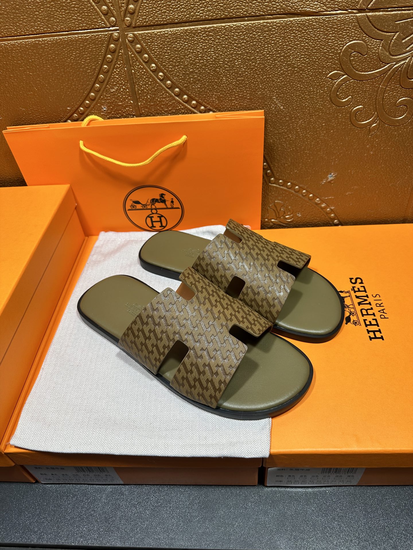 Hermes slide sandals with dark monogram-like pattern and black cutout strap tabs