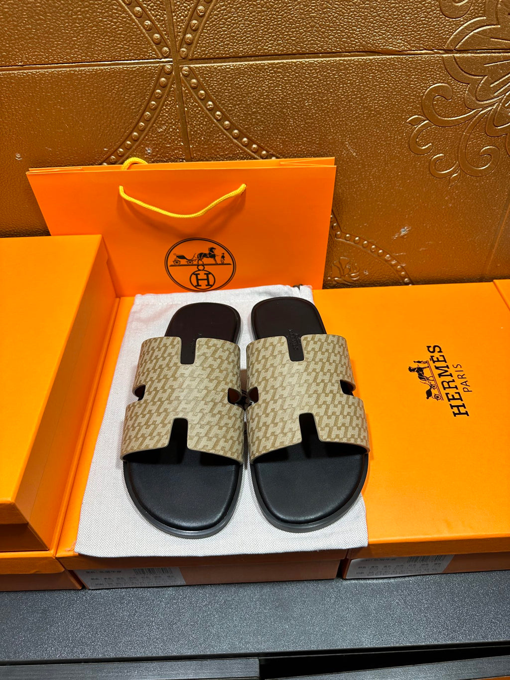 Beige and black slide sandals with patterned crossover straps and black sole