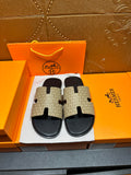 Beige and black slide sandals with patterned crossover straps and black sole