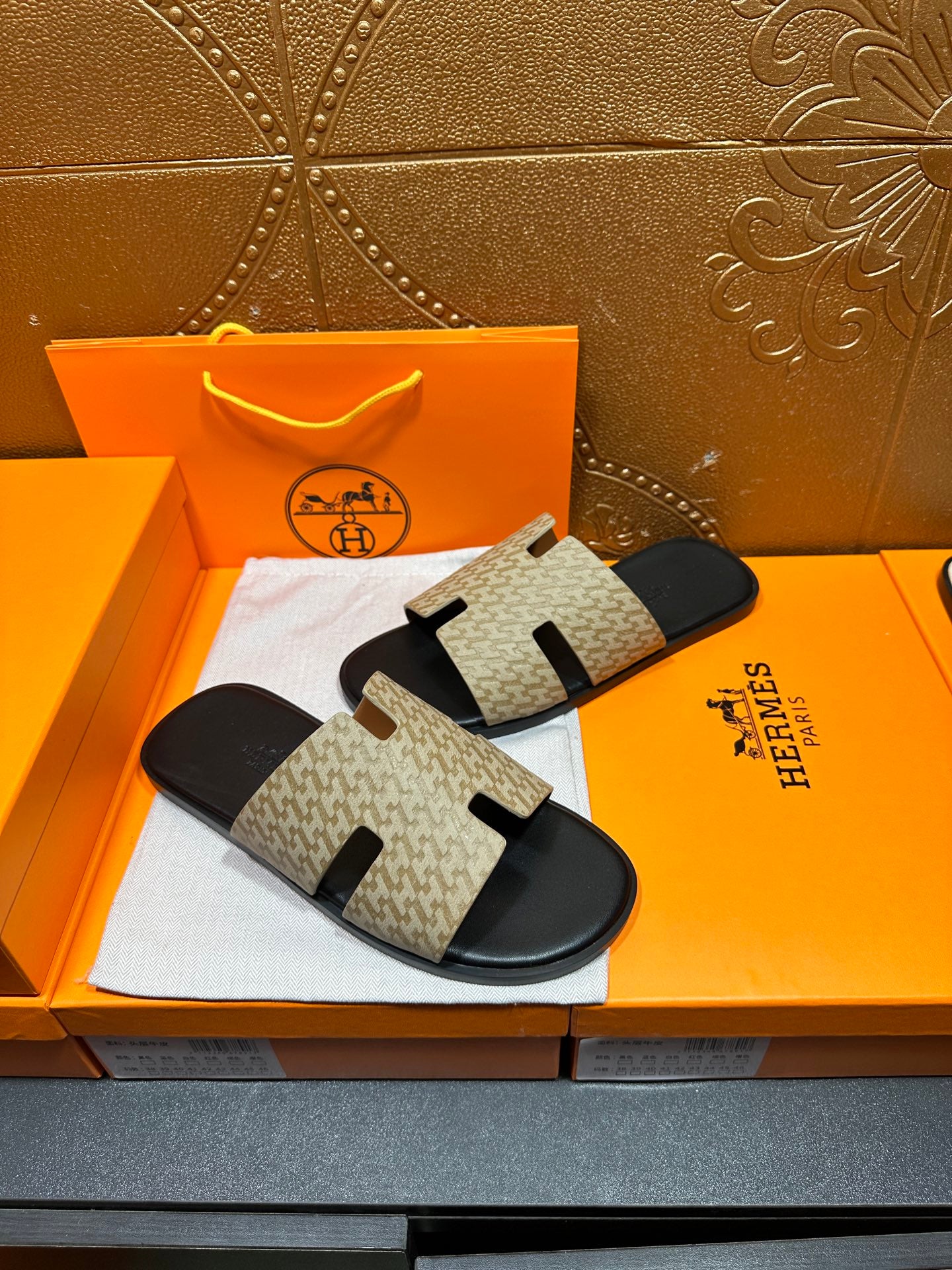Beige patterned slide sandals with black strap panels and rounded black toe