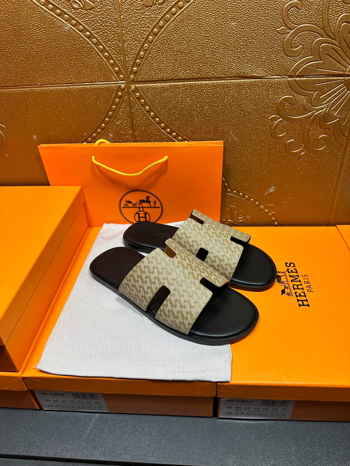 Pair of beige and black slide sandals with patterned upper and black sole