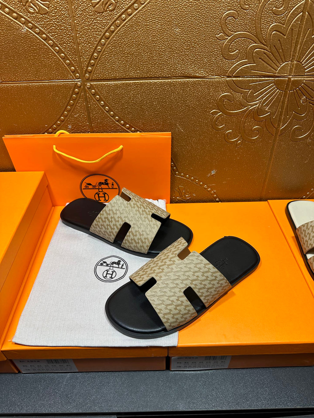 Beige and black slide sandals with patterned straps and black footbed