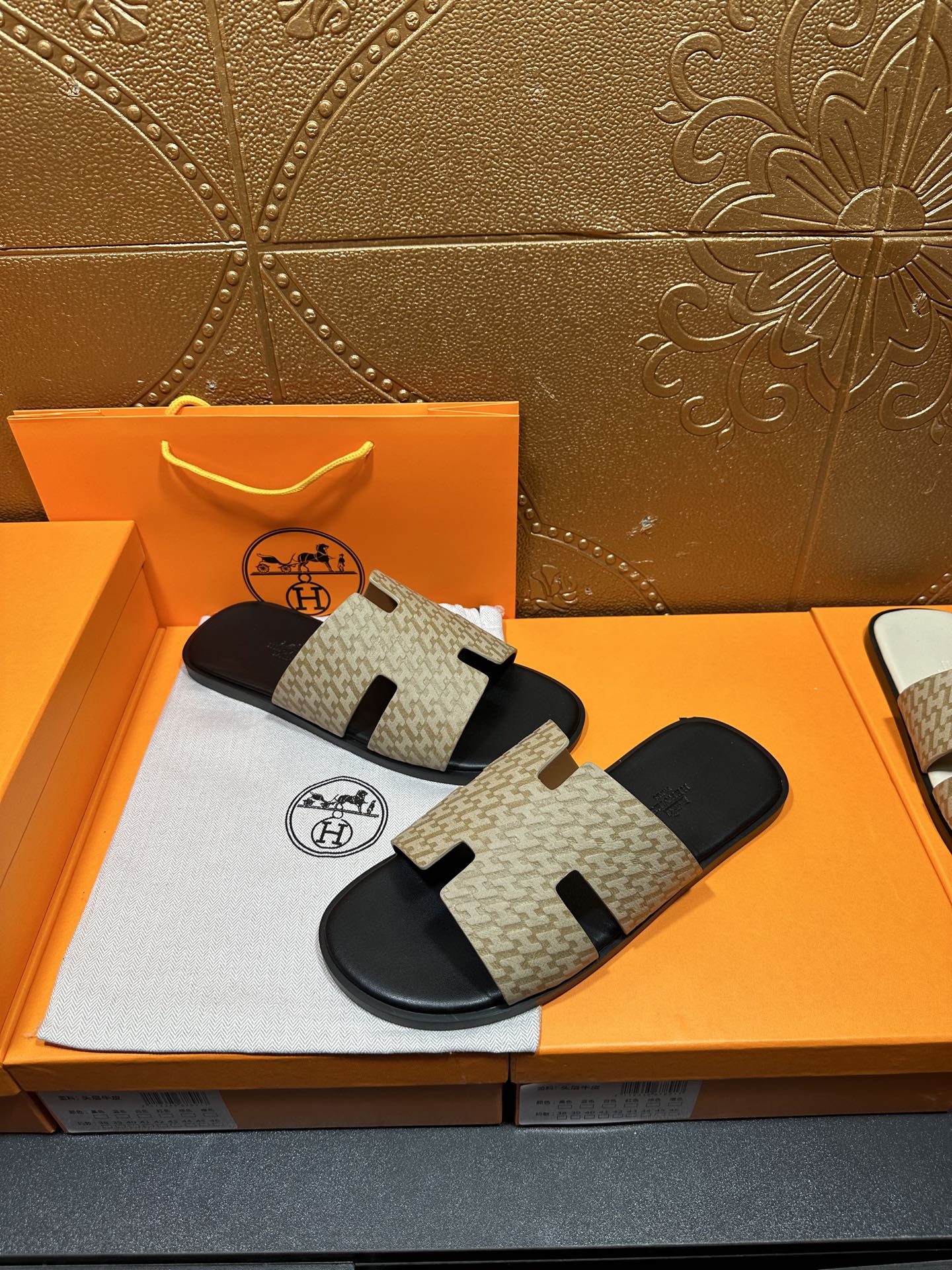 Beige and black slide sandals with patterned straps and black footbed