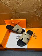 Beige and black slide sandals with patterned upper and black sole