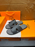 Hermes slide sandals, side view, dark patterned upper over black rubber footbeds