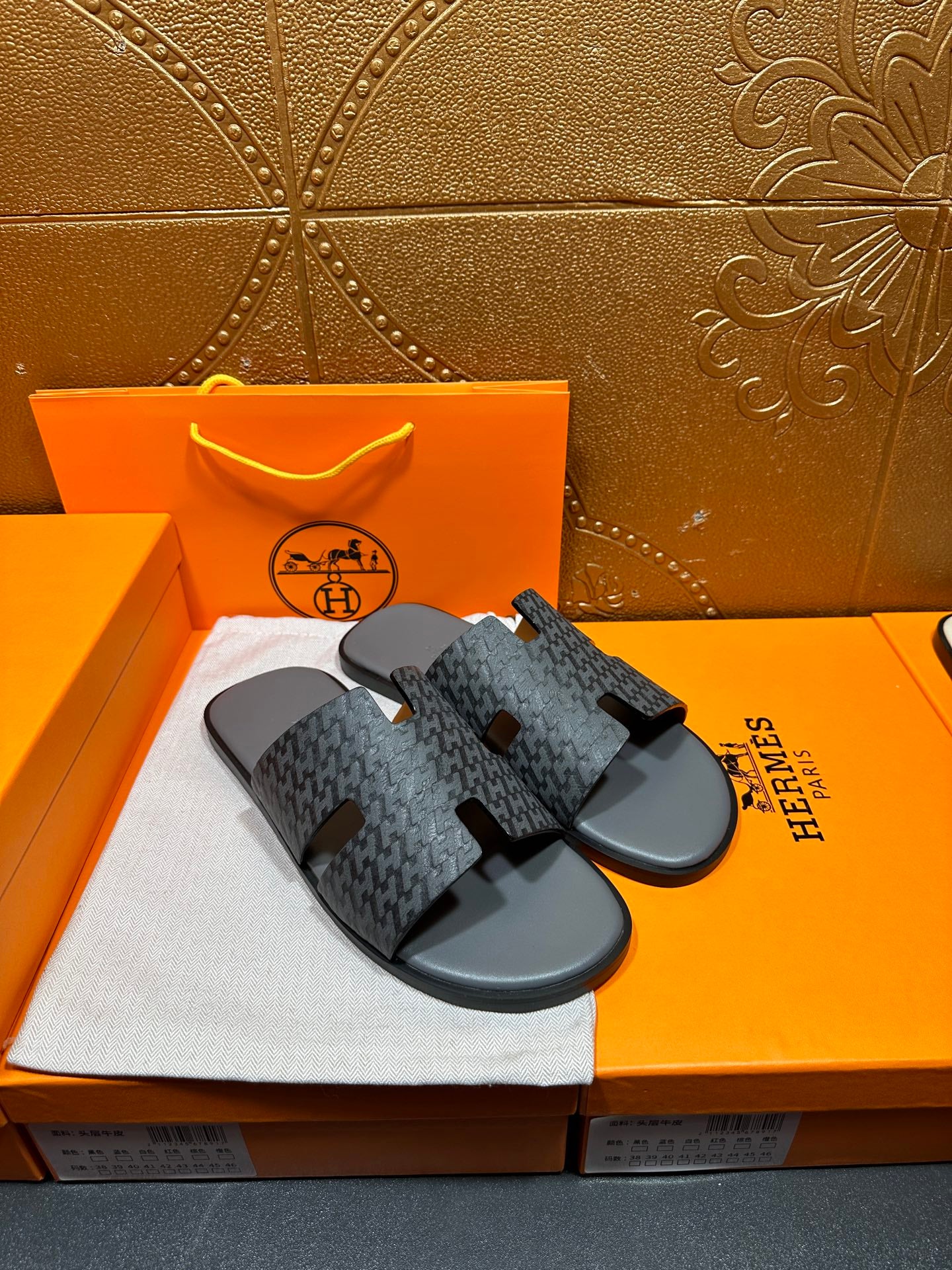 Hermes slide sandals pair, angled view, dark patterned straps on black rubber soles