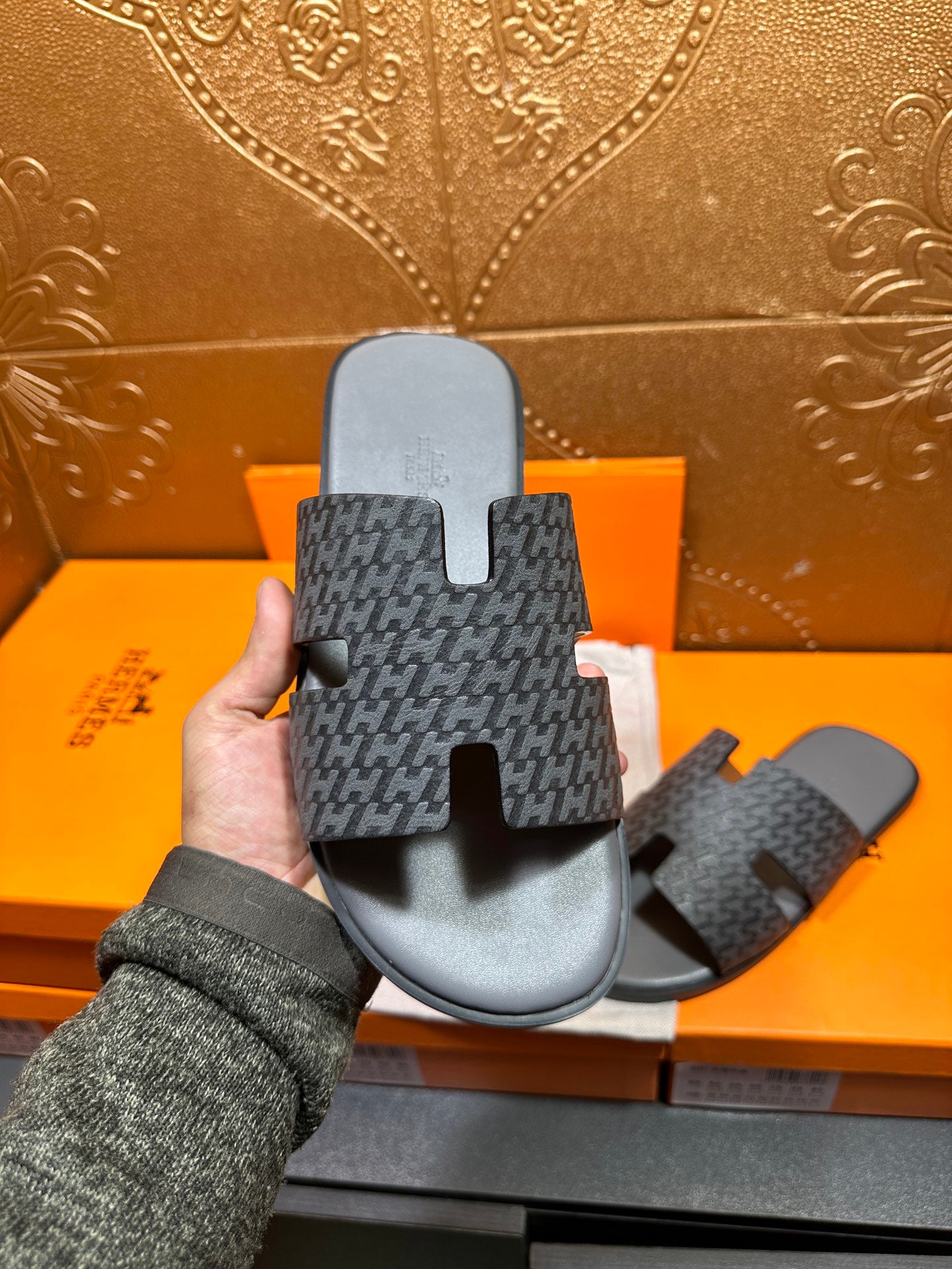 Hermes slide sandals, underside view, dark patterned upper with black H-style strap cutouts