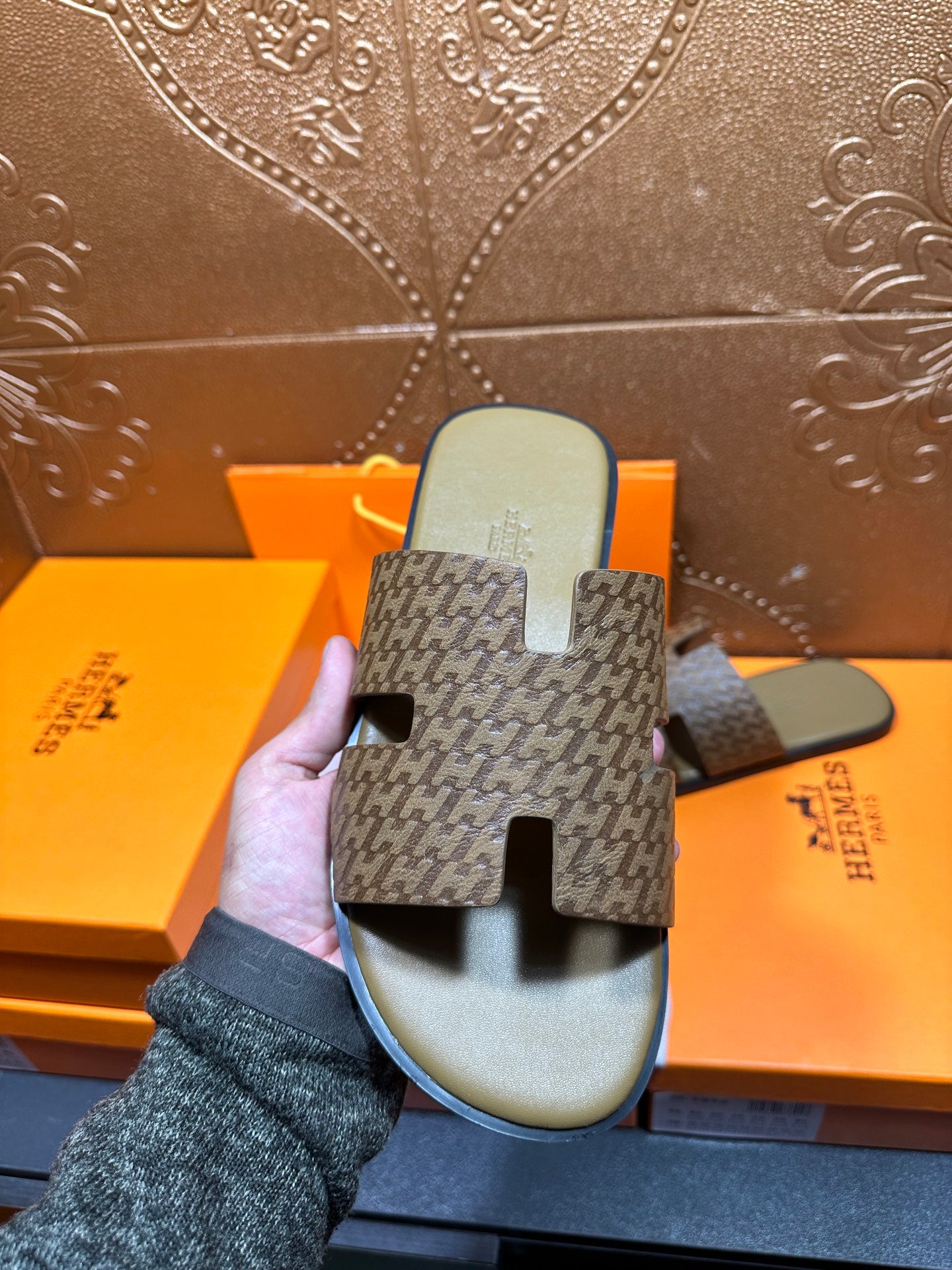 Hermes slide sandals held up: textured patterned straps and olive-green footbed soles