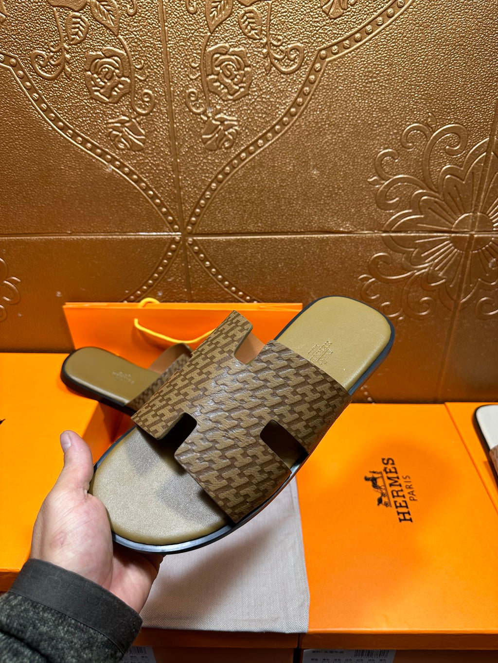 Hermes slide sandals laid flat: patterned upper with black cutout detail and olive footbeds