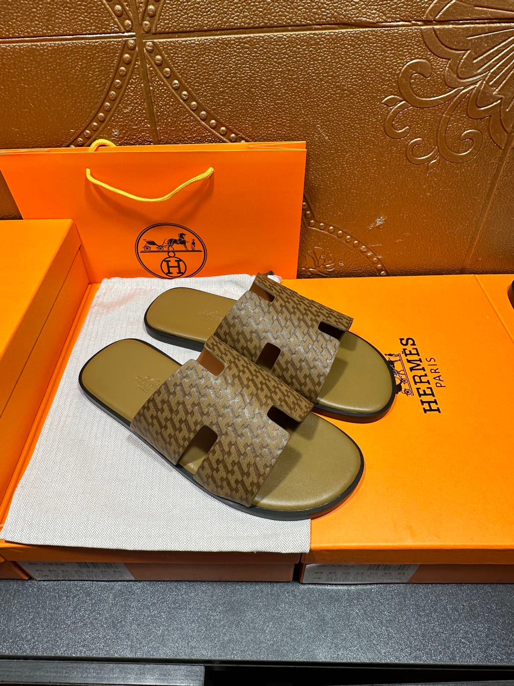 Pair of Hermes slide sandals with open-toe patterned straps and olive-green footbeds