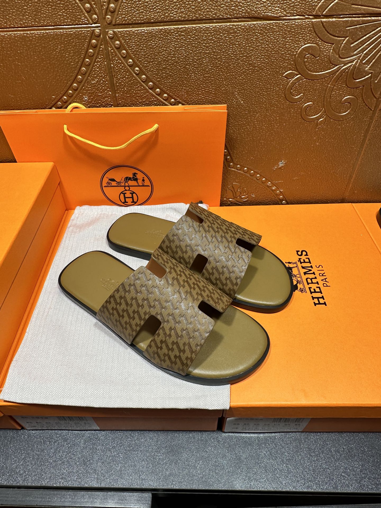 Pair of Hermes slide sandals with open-toe patterned straps and olive-green footbeds