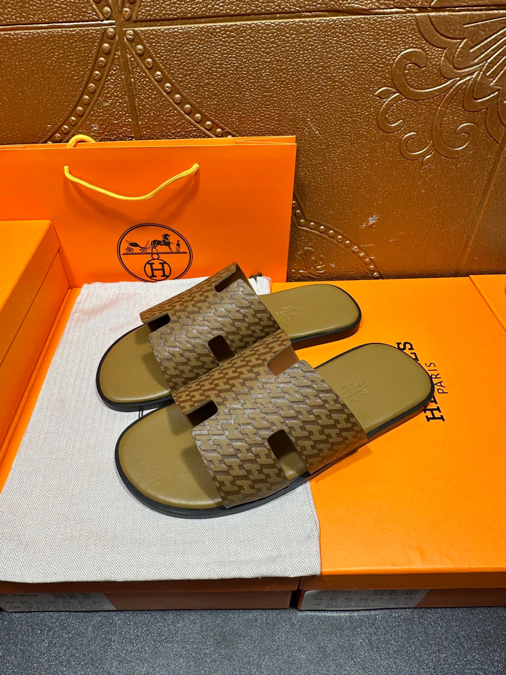 Hermes slide sandals showing patterned upper with black logo-like cutout accents