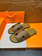 Hermes slide sandals showing patterned upper with black logo-like cutout accents