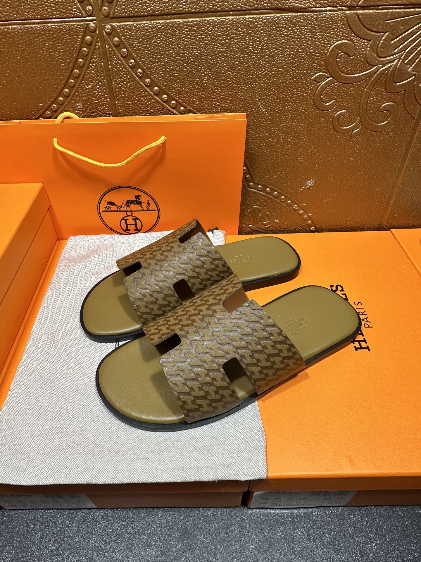 Hermes slide sandals showing patterned upper with black logo-like cutout accents