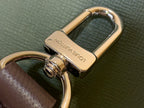 Gold-tone bag clasp hardware with leather strap on olive fabric