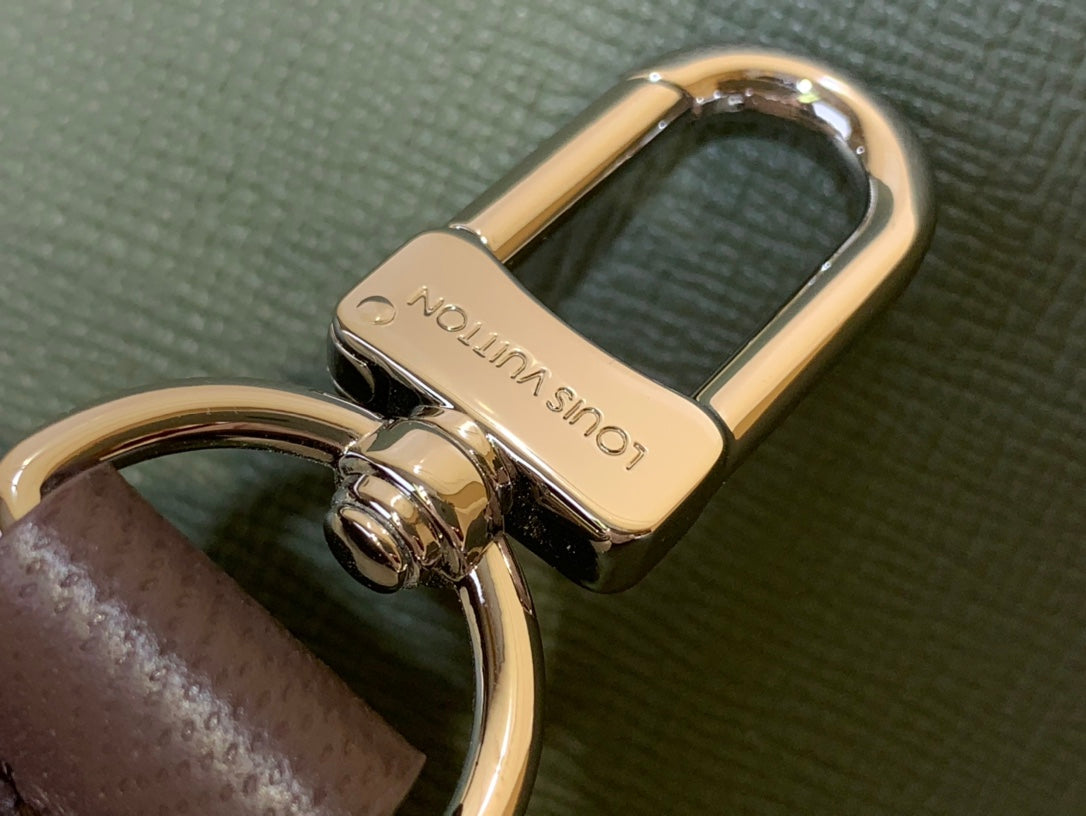 Gold-tone bag clasp hardware with leather strap on olive fabric