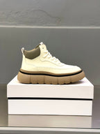 White lace-up sneakers with chunky tan sole and stitched toe detail, side profile