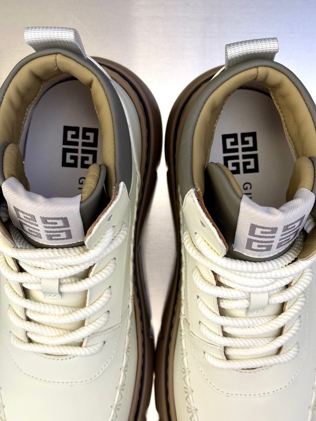 Pair of white sneakers with white laces and branded tongue lining, close-up view