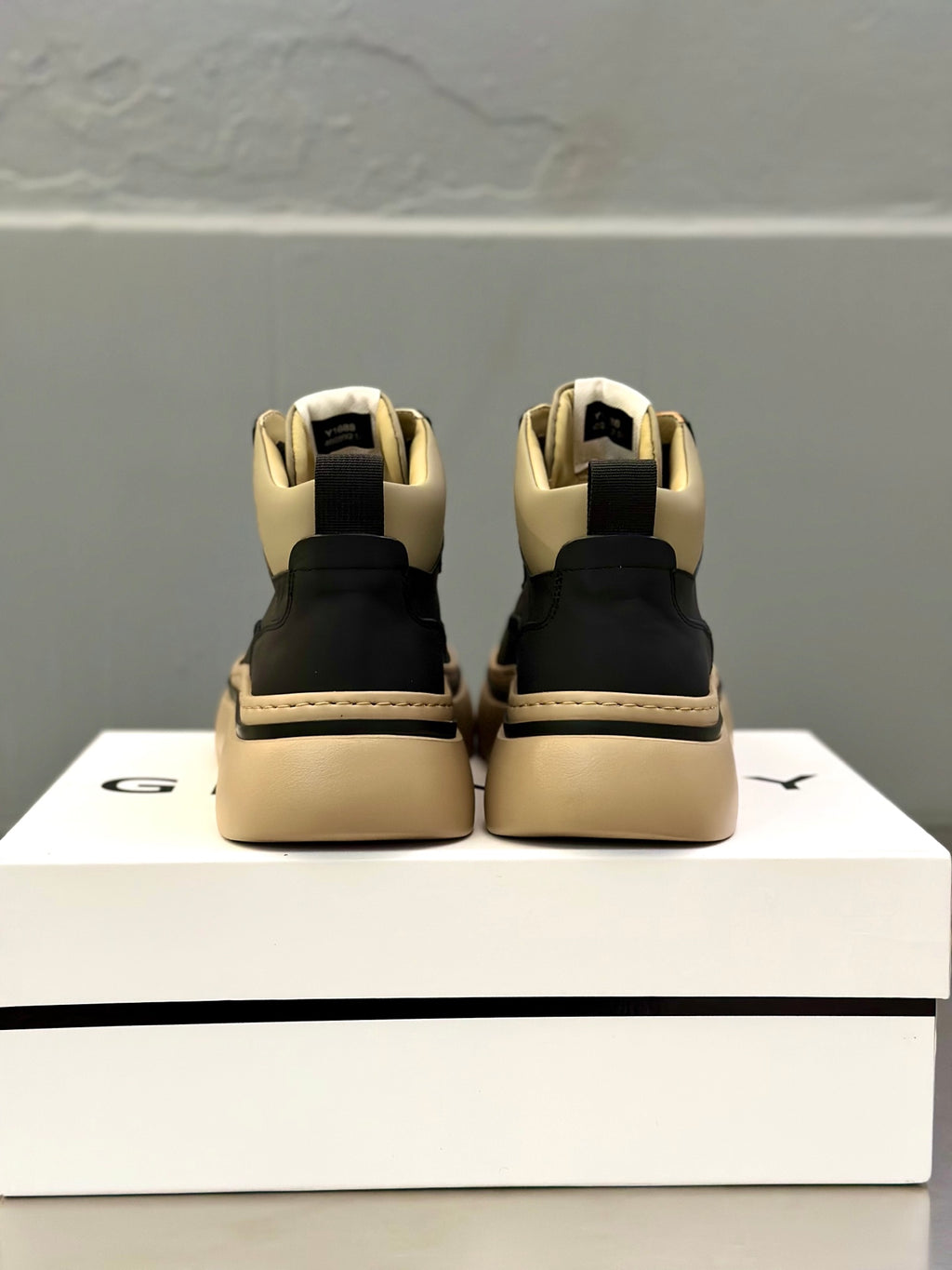 Back view of lace-up sneakers: dark upper with beige heel panels and platform sole.