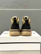Back view of black sneakers on display box, beige heel detailing and collar logo