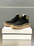Dark high-top sneakers with chunky sole, lace-up front and logo patch on tongue.