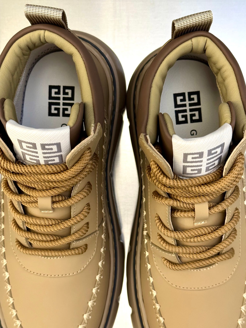Givenchy lace-up sneakers close-up, tan leather with GG logo tongue and laces