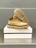 Beige leather sneakers with tread sole visible, lace-up front, and stitched trim