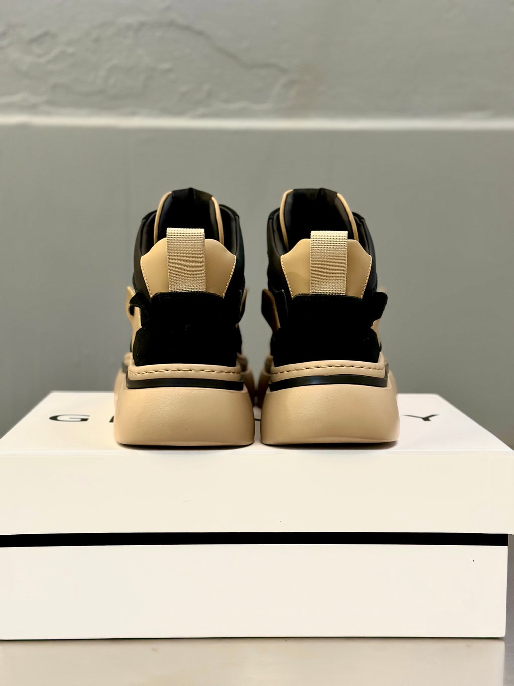 Back view of black and beige lace-up sneakers with heel strap and padded collar.