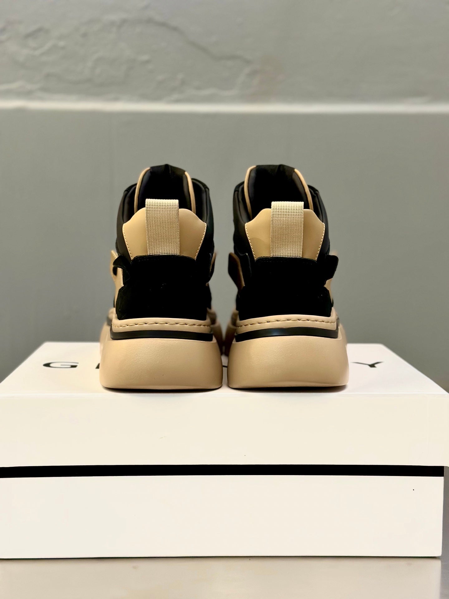 Back view of black and beige lace-up sneakers with heel strap and padded collar.