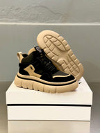 Black and beige lace-up sneakers with visible tread sole and raised outsole pattern.