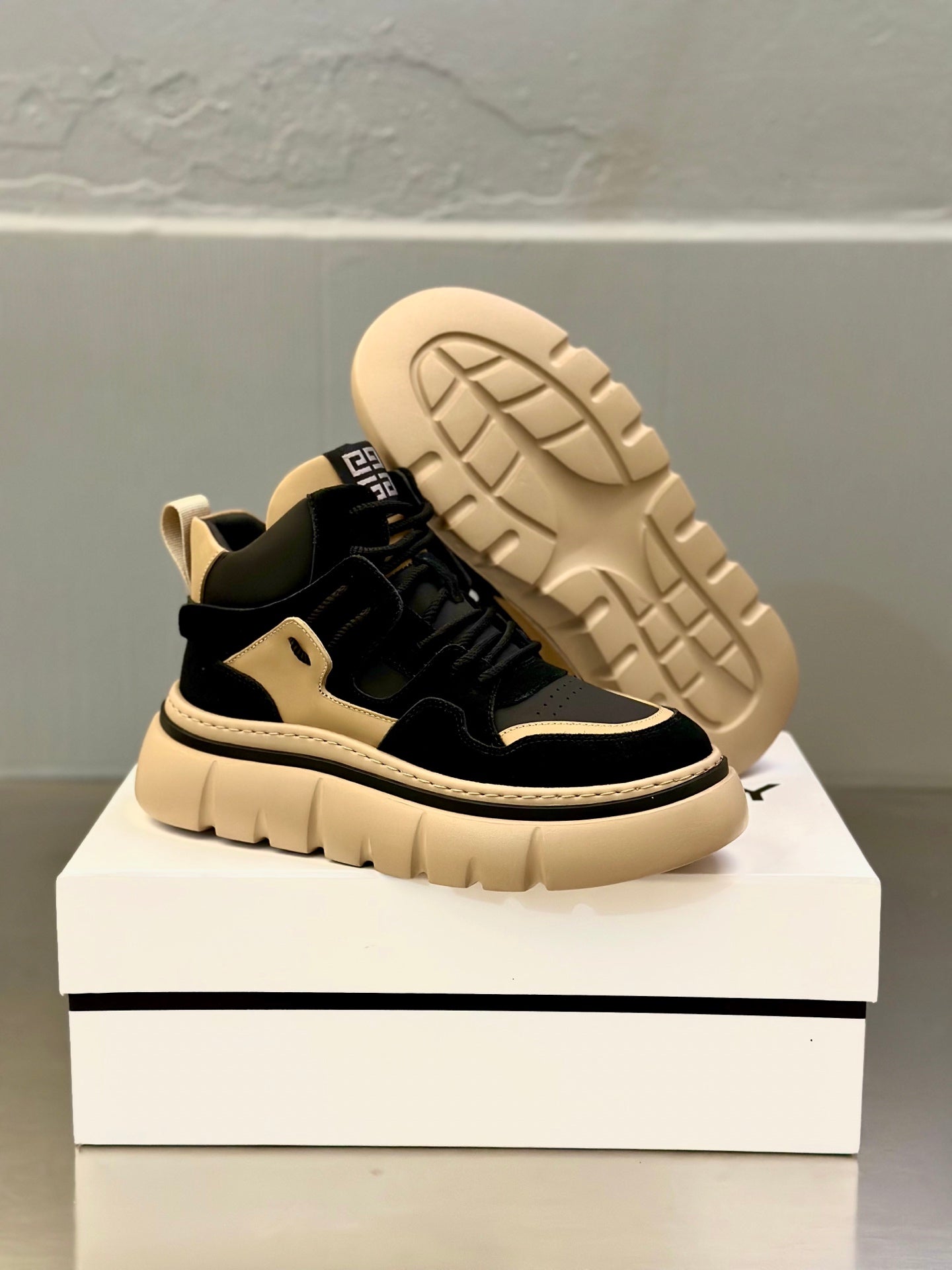 Black and beige lace-up sneakers with visible tread sole and raised outsole pattern.