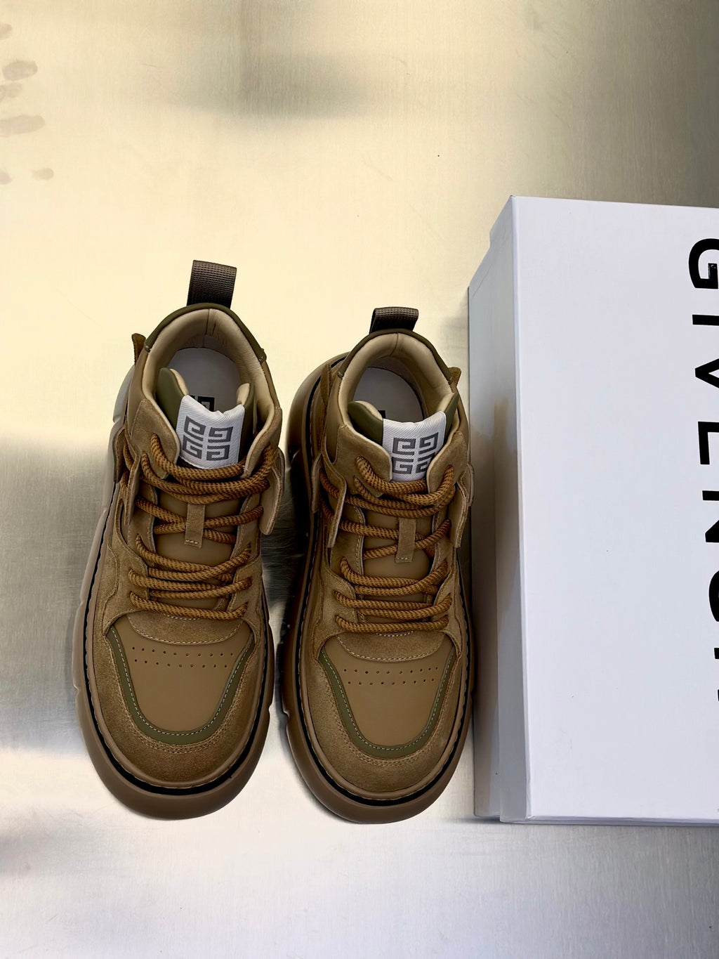 Olive-brown suede sneakers with lace-up front, padded collar, and chunky rubber sole.