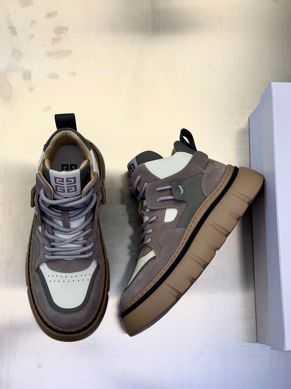 Pair of gray and white lace-up sneakers with chunky beige outsole and heel tabs